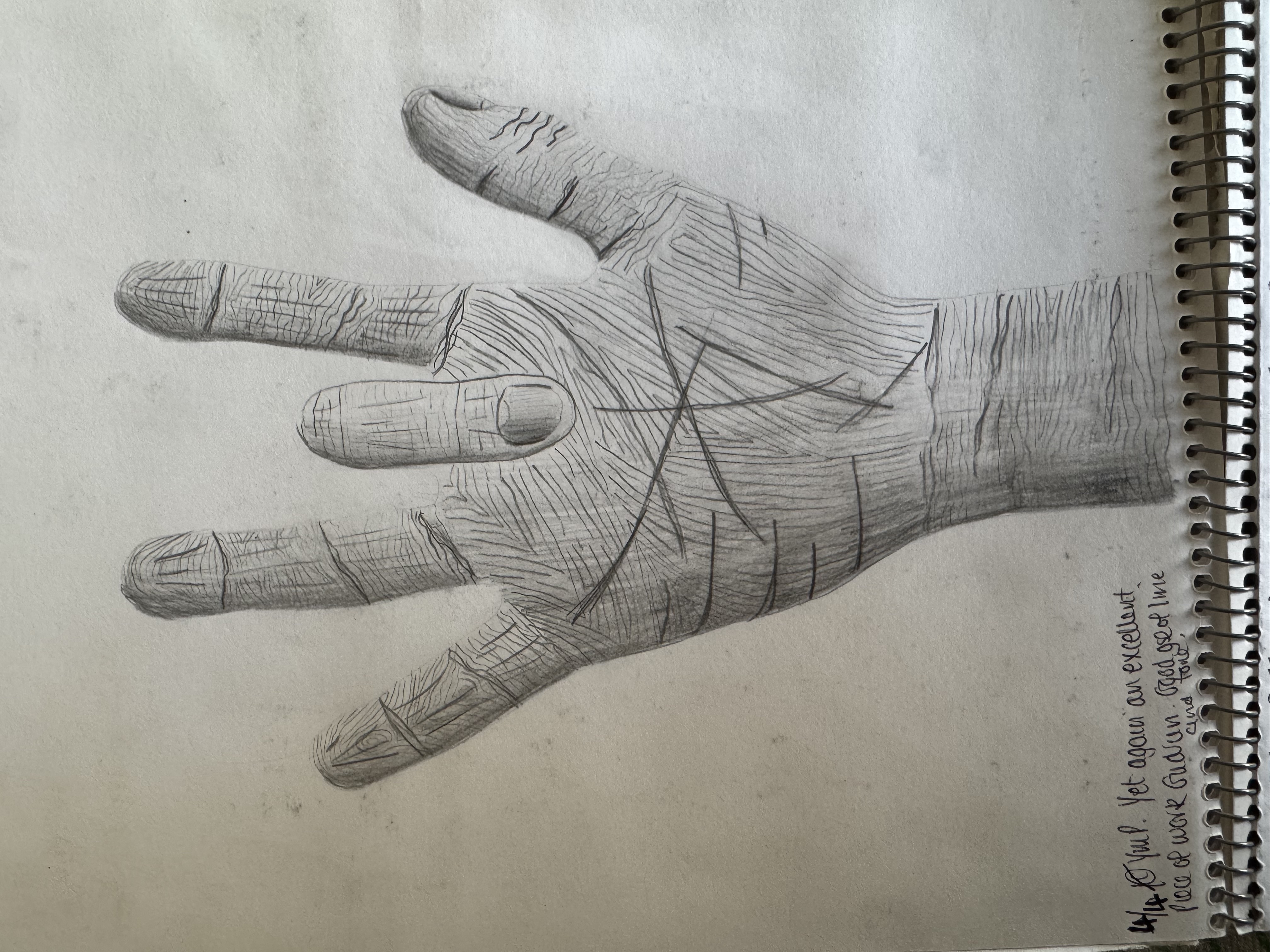 Pencil drawing of a hand from age eleven, with teacher note and spiral edge